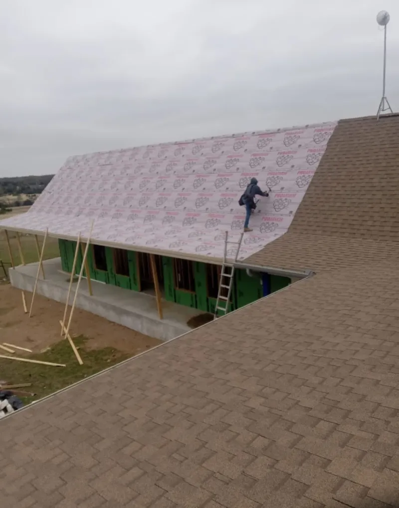 Worker preparing underlayment for a metal roof installation in Ontwa